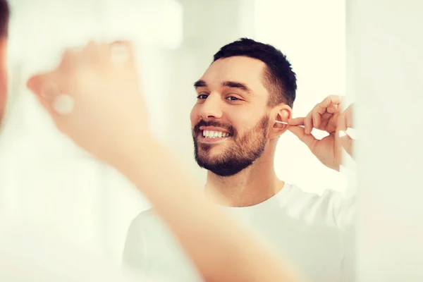 Man cleaning ear with cotton swab at bathroom — Stock Photo, Image