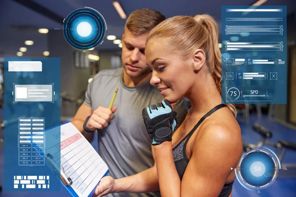 Smiling woman with trainer and clipboard in gym — Stock Photo, Image