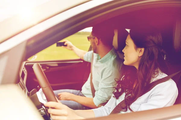 Feliz pareja en coche tomando selfie con smartphone —  Fotos de Stock