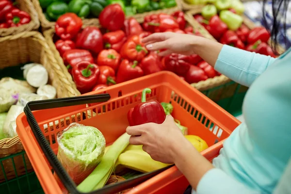 Mujer con cesta comprando pimientos en la tienda de comestibles — Foto de Stock