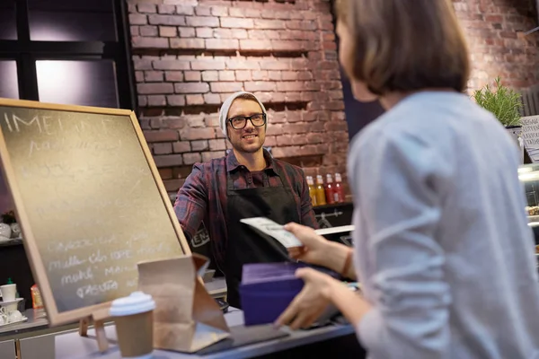 Happy barman a žena platí peníze v kavárně — Stock fotografie