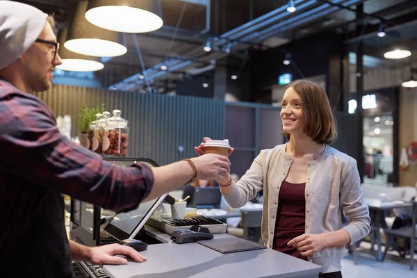 Seller giving coffee cup to woman customer at cafe — Stock Photo, Image
