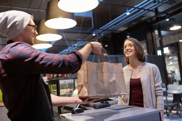 Vendedor dando saco de papel ao cliente no café vegan — Fotografia de Stock