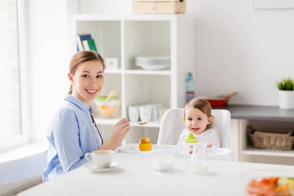 Mère heureuse nourrissant bébé avec purée à la maison — Photo