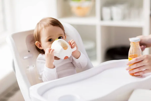 Baby trinkt aus Auslaufbecher im Hochstuhl zu Hause — Stockfoto