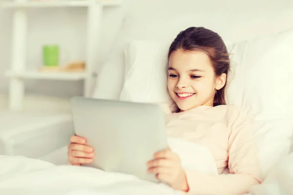 Happy girl lying in bed with tablet pc at home — Stock Photo, Image