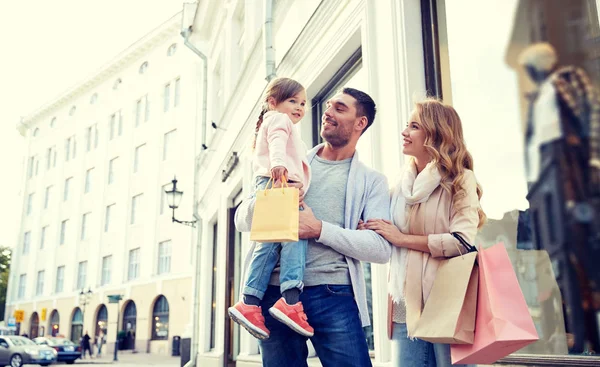 Família feliz com criança e sacos de compras na cidade — Fotografia de Stock