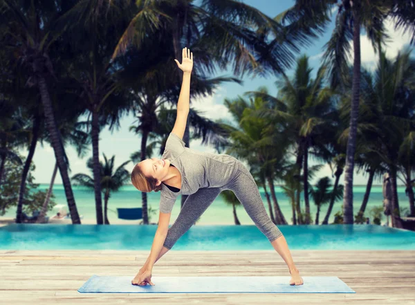 Vrouw maken yoga driehoek pose op de mat — Stockfoto