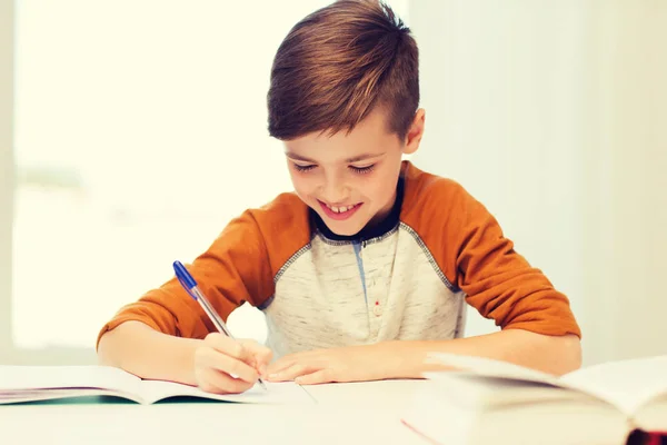 Sorridente studente ragazzo scrivendo per notebook a casa — Foto Stock