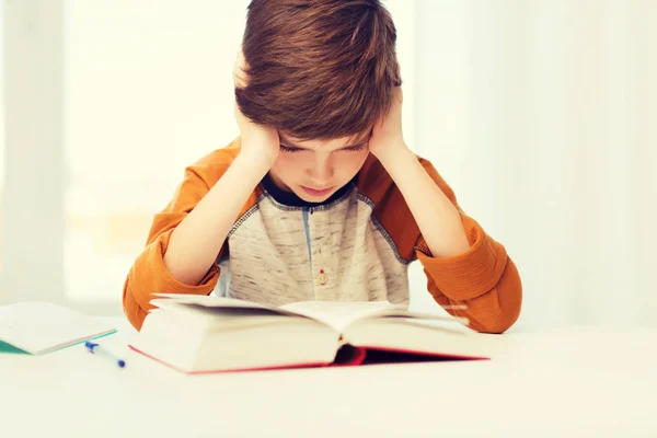 Student pojke läsa bok eller lärobok hemma — Stockfoto