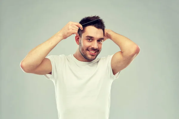 Glücklicher Mann, der Haare mit Kamm über Grau streicht — Stockfoto