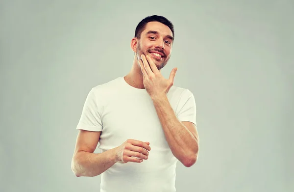 Felice giovane uomo applicando crema o lozione per il viso — Foto Stock