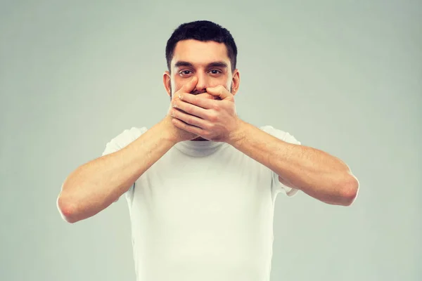 Человек в белой футболке закрывает рот руками — стоковое фото