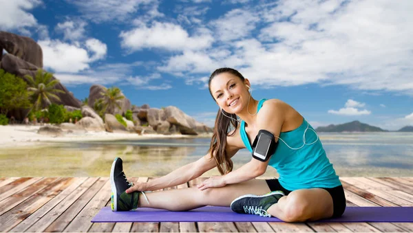 Donna con smartphone allungamento gamba su tappetino — Foto Stock