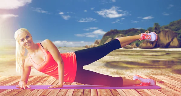 Mulher sorrindo fazendo exercícios no tapete ao ar livre — Fotografia de Stock