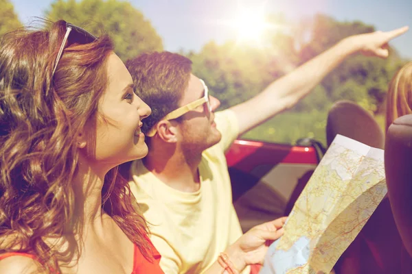 Amigos felizes com mapa dirigindo em carro cabriolet — Fotografia de Stock