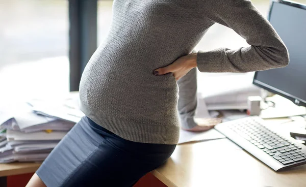 W ciąży kobieta siedzi na stół w biurze — Zdjęcie stockowe