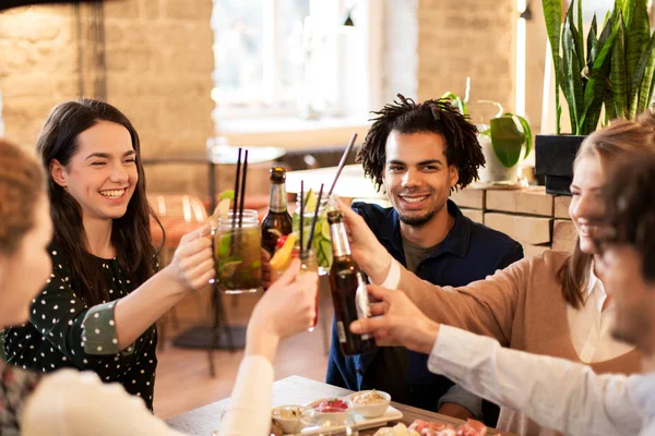 Happy friends with drinks at bar or cafe — Stock Photo, Image