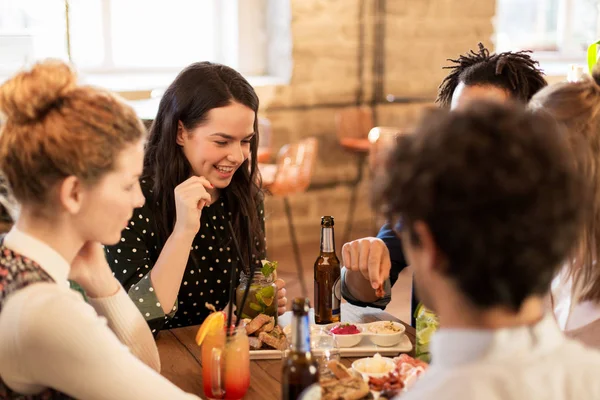 Happy vrienden eten en drinken bij bar of café — Stockfoto