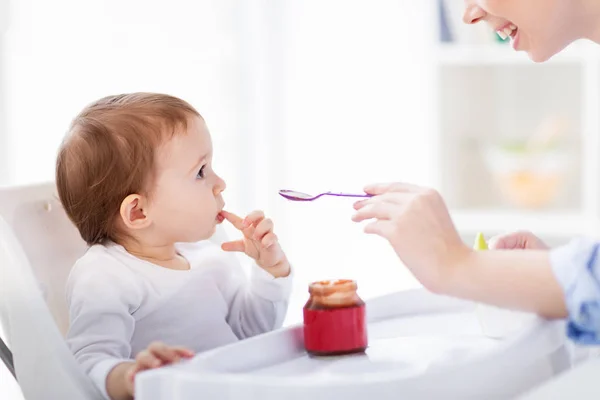 Mãe feliz alimentando bebê com purê em casa — Fotografia de Stock