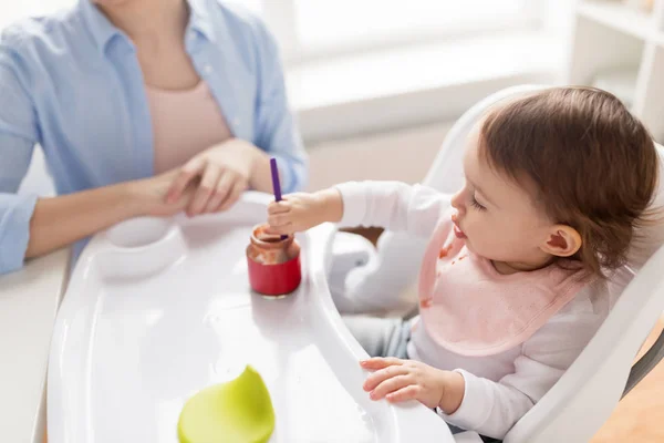 Bambina con cucchiaio mangiare purea dal barattolo a casa — Foto Stock