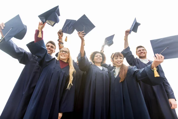 Happy students or bachelors waving mortar boards — Stock Photo, Image