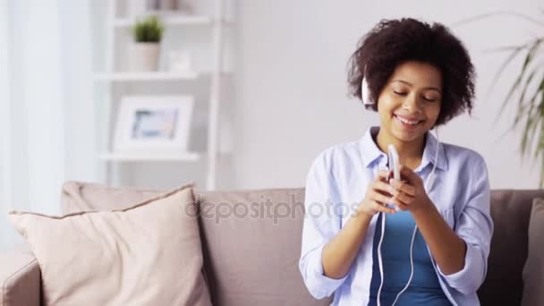 Mujer con smartphone y auriculares en casa — Vídeo de stock