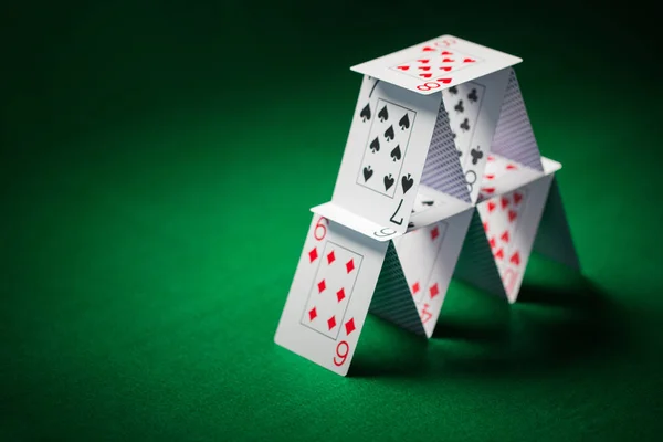 Casa de cartas de jogar na toalha de mesa verde — Fotografia de Stock
