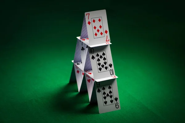 Casa de cartas de jogar na toalha de mesa verde — Fotografia de Stock