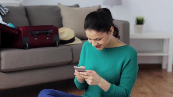 Жінка зі смартфоном вдома збирається подорожувати — стокове відео