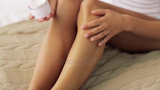 Hermosa mujer aplicando crema a sus piernas en casa — Vídeo de stock
