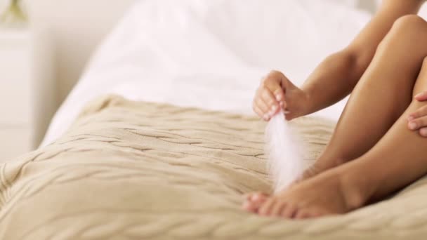 Žena s pérem dotýkat bosé nohy na postel — Stock video