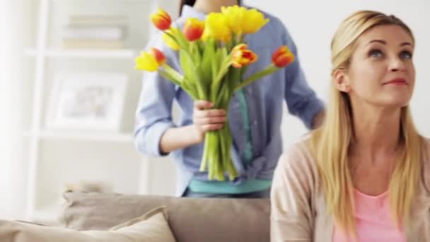 Lycklig flicka ger blommor till mamma hemma — Stockvideo