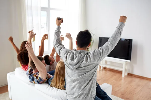 Amigos felizes com cerveja assistindo tv em casa — Fotografia de Stock