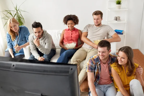 Happy přátelé s popcorn sledování televize u vás doma — Stock fotografie