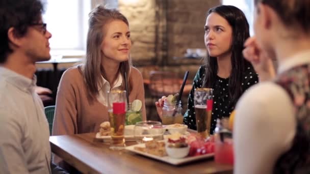 Amigos felices comiendo y bebiendo en el restaurante — Vídeo de stock