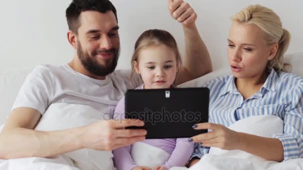 Щаслива сім'я з планшетним ПК в ліжку вдома — стокове відео
