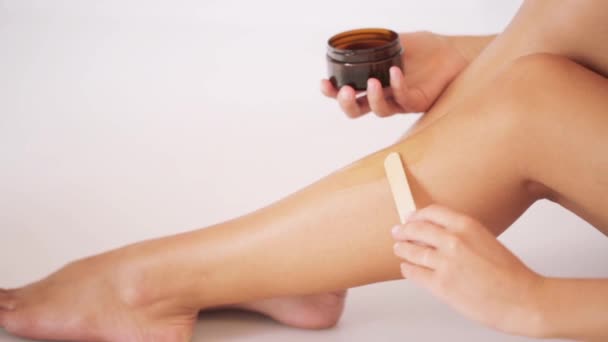 Hermosa mujer aplicando cera depilatoria a su pierna — Vídeo de stock