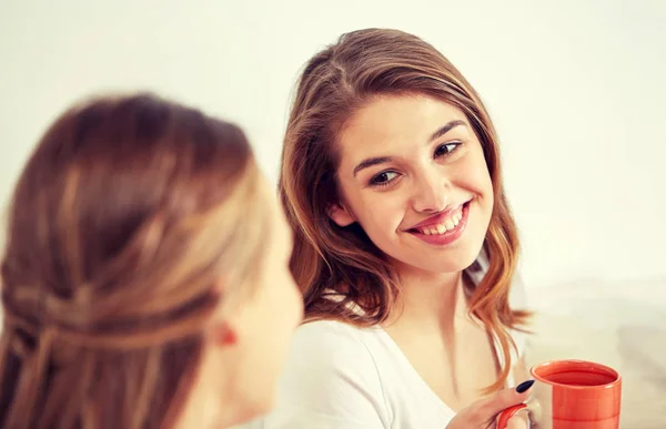 Happy young women drinking tea with sweets at home — Stock Photo, Image