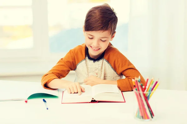 Lächelnder, studierender Junge, der zu Hause Buch liest — Stockfoto
