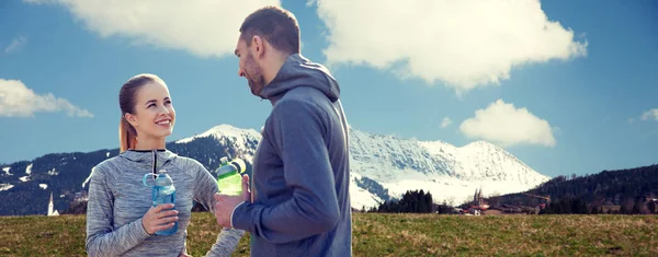 Pareja sonriente con botellas de agua al aire libre — Foto de Stock