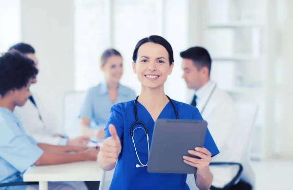 Zufriedener Arzt mit Tablet-PC über Team in Klinik — Stockfoto