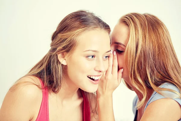 快乐的年轻妇女，耳语八卦在家里 免版税图库图片