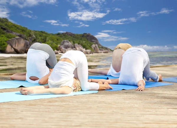 Група людей, що роблять вправи на йогу над пляжем — стокове фото