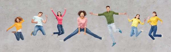 Personas felices o amigos saltando en el aire sobre gris —  Fotos de Stock