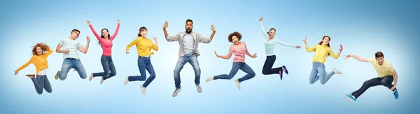 Glückliche Menschen oder Freunde, die in der Luft über blau springen — Stockfoto