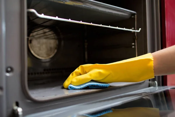 Το χέρι με πανί καθαρισμού στο σπίτι φούρνο κουζίνας — Φωτογραφία Αρχείου