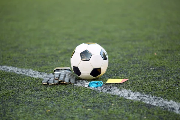 Ball, gloves, whistle and cards on soccer field — Stock Photo, Image