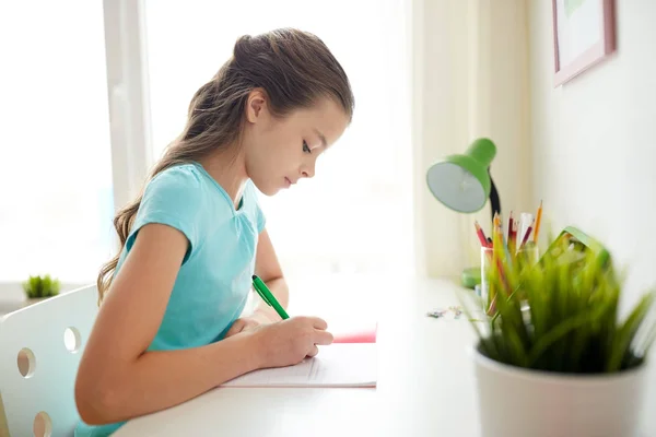 Chica escribiendo a cuaderno en casa — Foto de Stock