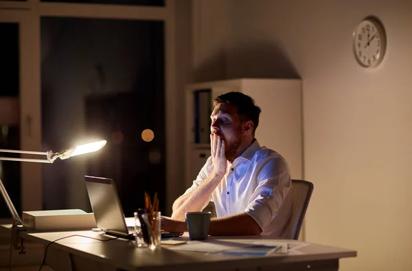 Hombre con portátil y café trabajando en la oficina de noche —  Fotos de Stock